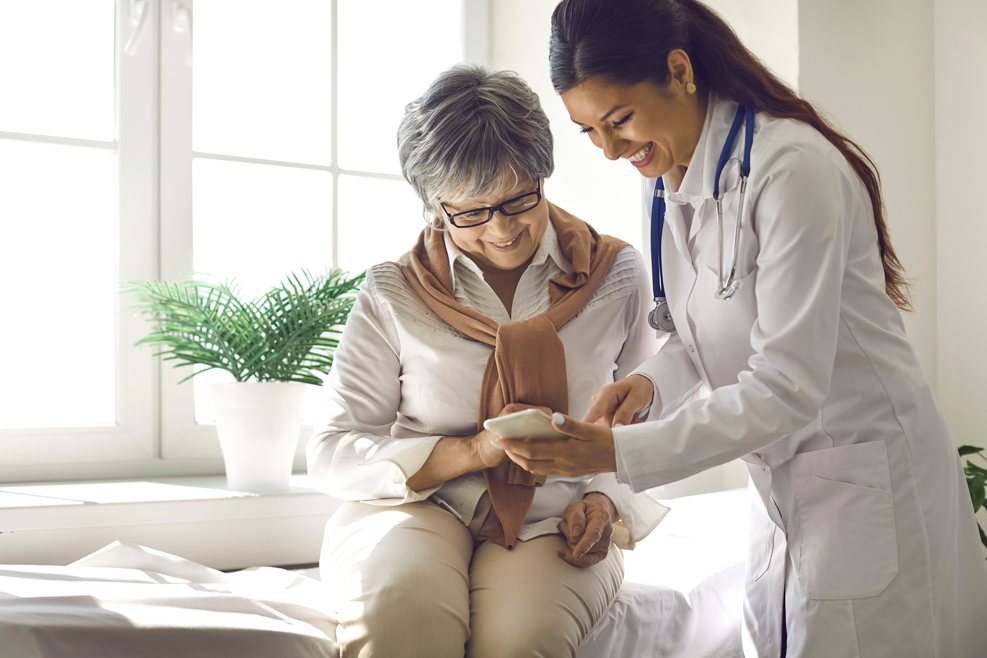 provider showing alternative payment models in healthcare to senior patient sitting in bright doctors office